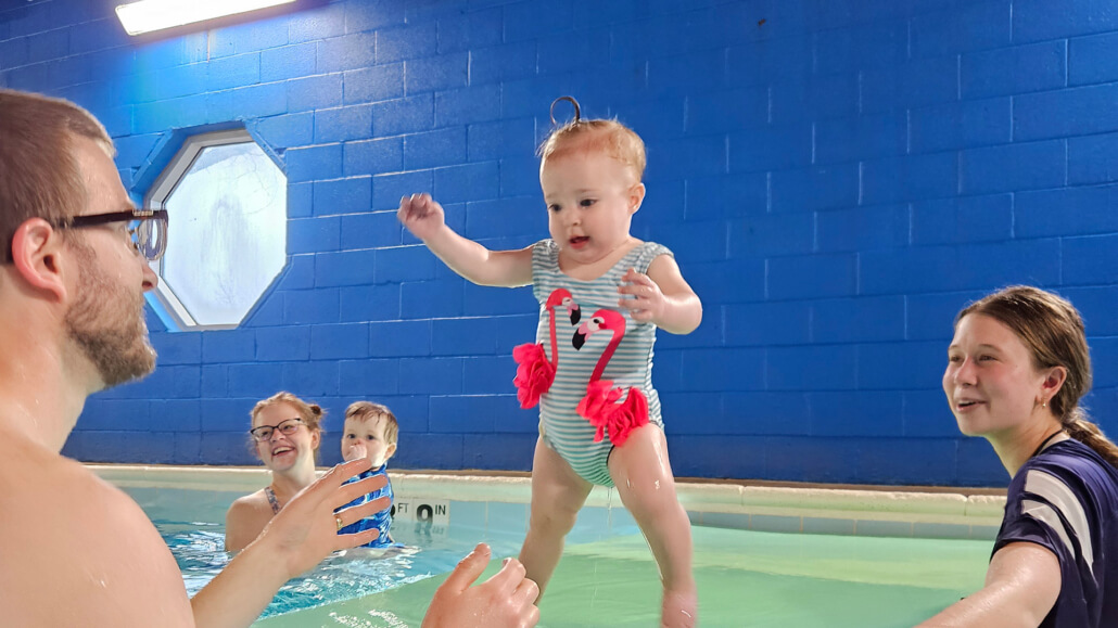 Excited baby standing up in the pool during Baby Swim at Dolphin Swim Club in Loves Park