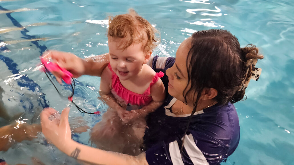 Instructor helping a toddler with goggles in a Level A swim class at Dolphin Swim Club in Loves Park