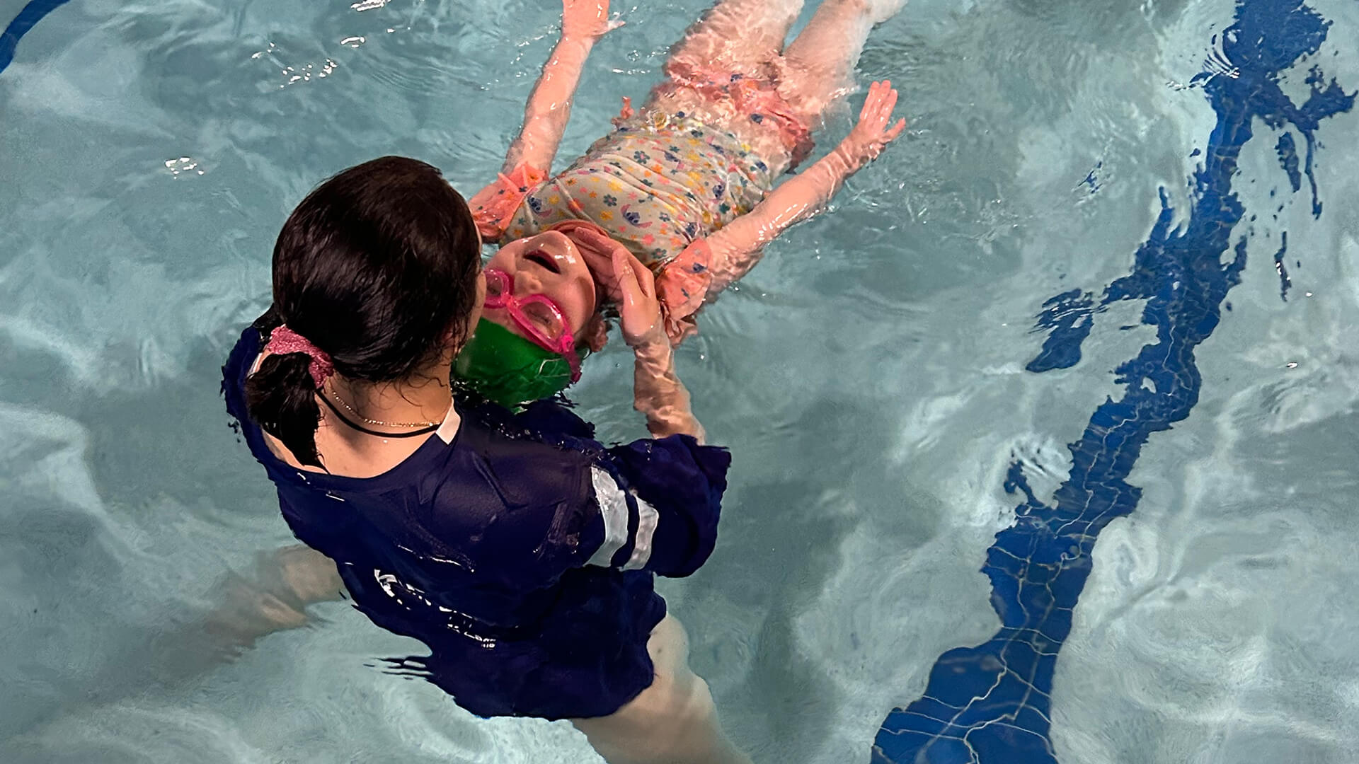 Instructor helping a swimmer practice a back float at Dolphin Swim Club in Loves Park